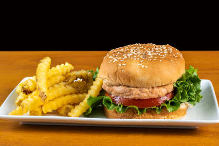 salmon burger   on a sesame bun  served with a side of friesの写真素材