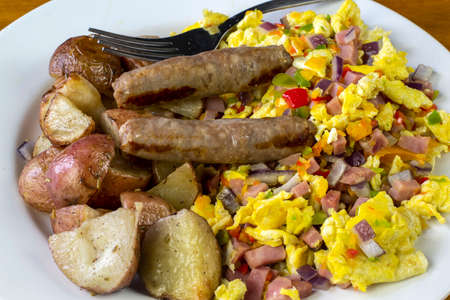 eggs scrambled  with onions ham and peppers served with sausage and potatoesの写真素材