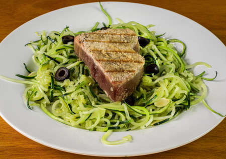 tuna steak  served with zucchini noodles and black olivesの写真素材