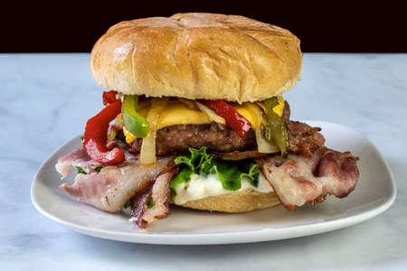bacon cheese burger top with sauteed peppers and onionsの写真素材