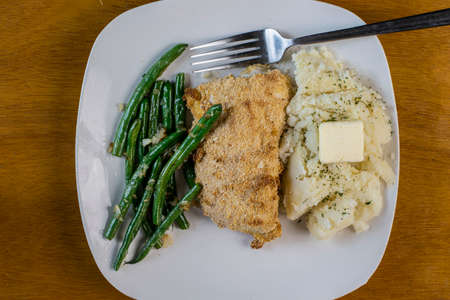 baked chicken thigh served with sateed beans  covered in onionss and mash potatoesの写真素材