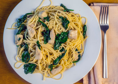 spaghetti served with sauteed spinach and chickenの写真素材