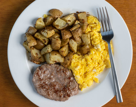 scramble eggs served with sausage patty and home friesの写真素材