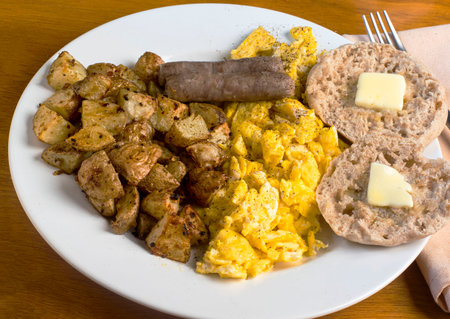 scramble eggs served with sausage, home fries and english muffinの写真素材