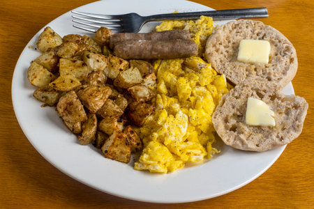 scramble eggs served with sausage, home fries and english muffinの写真素材