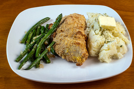 baked chicken thigh served with sateed beans  covered in onionss and mash potatoesの写真素材