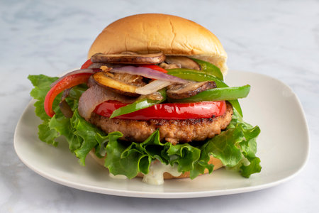 salmon burger top  with  sauteed peppers onions and mushroomsの写真素材