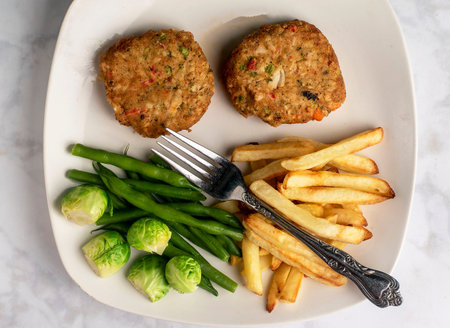 two lobstet cakes served with green beans and brussel sprouts,.の写真素材