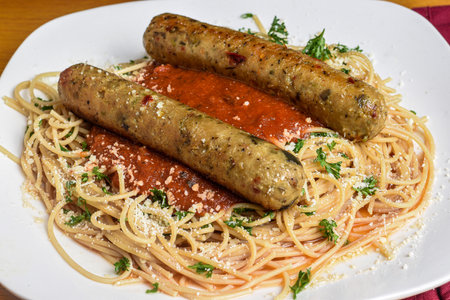 whole wheat spaghetti top with  sauce parsley and parmesan cheese served with plant based  sausage,の写真素材