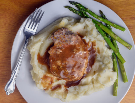 boneless pork chop resting on mashed potatoes  with gravy on topの写真素材