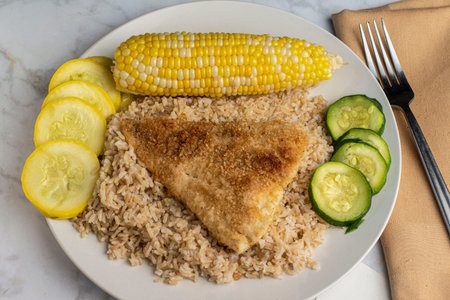 baked haddock   resting on  brown rice   served with  corn and dsquash,