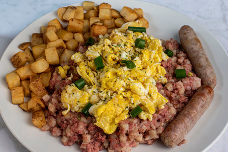 scramble egg top with parsley and green onions served with corn beef hash and hash brownsの写真素材