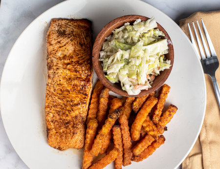 baked season salmon  served with cole slaw  and sweet potato friesの写真素材