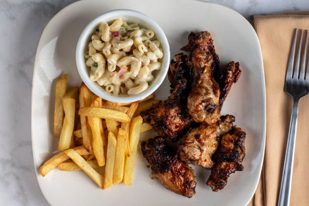 barbecue chiken wings served with macaroni salad and fries,の写真素材