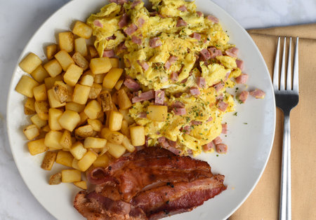 scramble egg with ham  served with  hash browns  and baconの写真素材