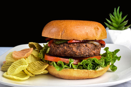 plant based burger with sauteed onions and peppers served with  veggie chipsの写真素材