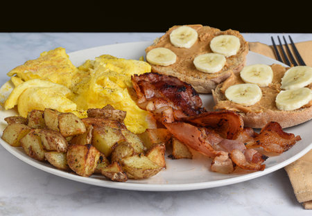 scramble  eggs  with  bacon  and home fries served with english muffins  and bananasの写真素材