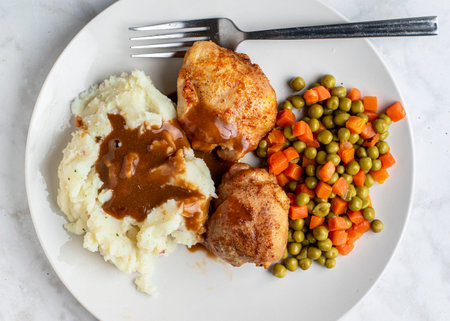 chicken thighs with mash potatoes and gravy  served with peas and carrotsの写真素材