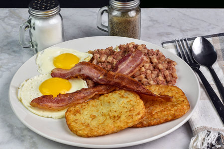 fried eggs served with bacon, corn beee hash and bacon