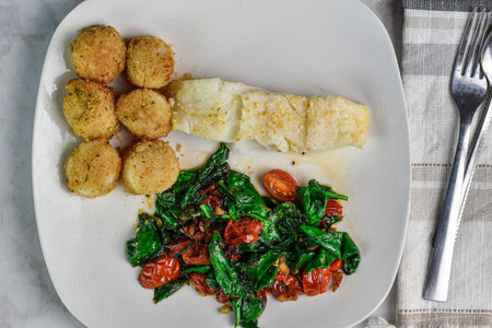 baked cod served with scallopsand sauteed spinach and tomatoes