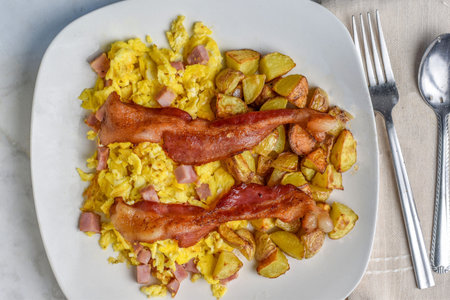 scramble eggs served with bacon and home friesの写真素材