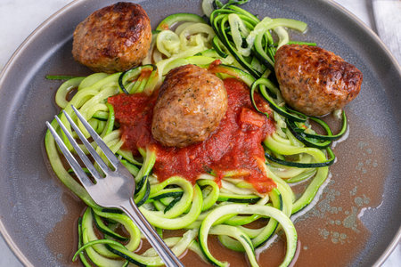 zucchini noodles top with pasta sauce and served with meat ballsの写真素材
