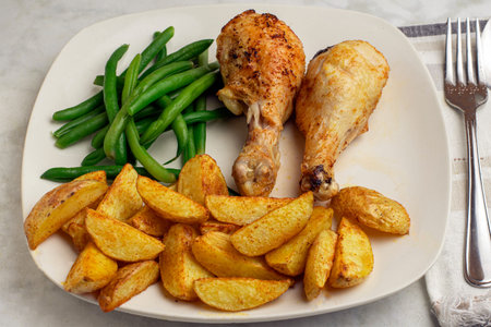 chicken drumsticks  served with greebn beans and potato wedgesの写真素材