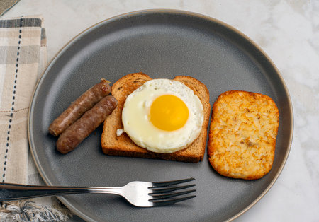 fried egg  on toast served with  breakfast sausage and home friesの写真素材