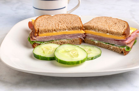 ham sandwich with lettuce . cheese and mayonnaise served with  cucumbersの写真素材