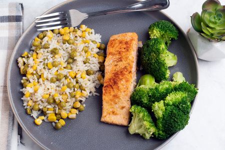 seasoned salmon  served with broccoli and rice mixed with corn and peasの写真素材