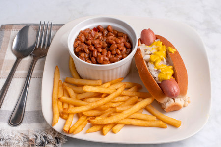 hot dog top with onions amd mustard served with baked beans and friesの写真素材