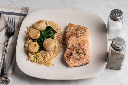 baked seasoned salmon  served with brown rice  spinach and pan sheared scallops.の写真素材