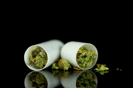 Medical Capsules of Cannabis - marijuana flower in capsules on the mirror black background.の写真素材