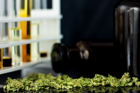 Medical Oil of Cannabis - oil test tubes with old antique apothecary jar with marijuana on the black mirror background.の写真素材