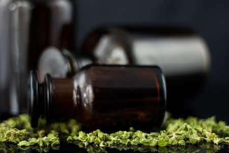 Medical Cannabis - view of marijuana in antique apothecary brown jar with dry marijuana on the black mirror background.の写真素材