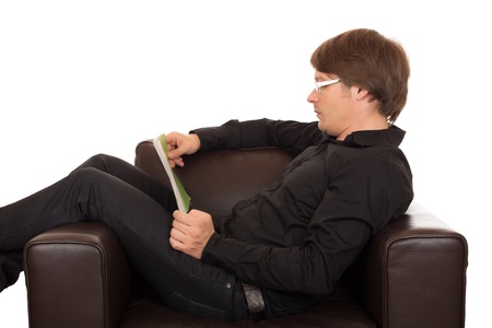 Man with glasses read a book quietly in his brown leather designed armchair. Isolated on white background.の写真素材