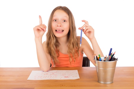 Child sitting at a table found an idea to draw. Isolated on a white background.の写真素材