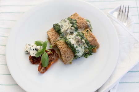 Tasty salty pancakes with spinach, roquefort, dried tomatoes and basil.の写真素材