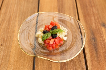 Caprese tartar in soup glass plate on a wooden table.の写真素材