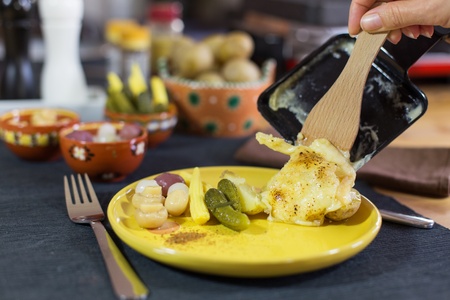 Raclette, traditional specialty of grilled yellow cheese, potatoes and pickles の写真素材