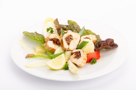 Plate of food with sliced stuffed chicken, endives, tomatoes and salad.の写真素材
