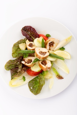 Plate of food with sliced stuffed chicken, endives, tomatoes and salad.の写真素材