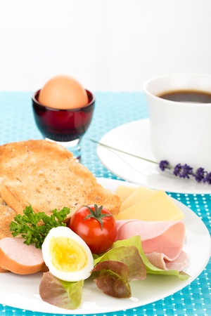 Breakfast with toast, cheese, sausage, ham, tomato, egg and cup of coffee.の写真素材