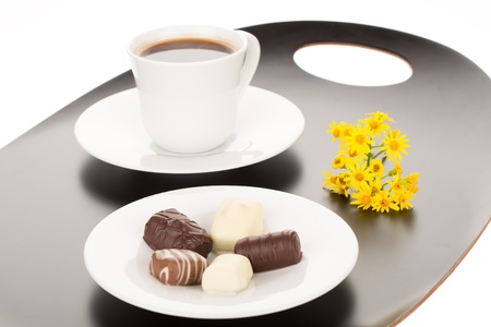 Chocolate assortment in white plate and cup of coffee.の写真素材