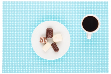 Chocolate assortment in white plate and cup of coffee.の写真素材