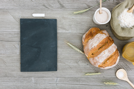 Homemade sourdough bread with flower, sourdough starter, salt, water and ears of wheat on a rustic table.の写真素材