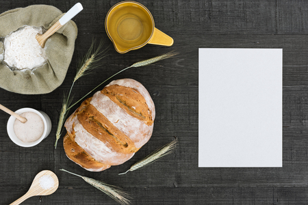 Homemade sourdough bread with flower, sourdough starter, salt, water and ears of wheat on a rustic table.の写真素材