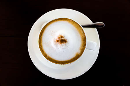 A cup of cappuccino and cinnamon isolated over black backgroundの写真素材