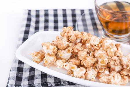 a white bowl filled with caramel coated popcornの写真素材