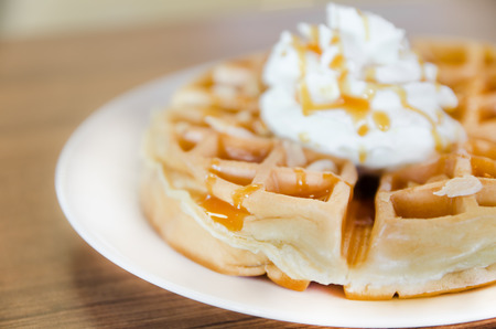 waffles under the caramel topping with cream on topの写真素材